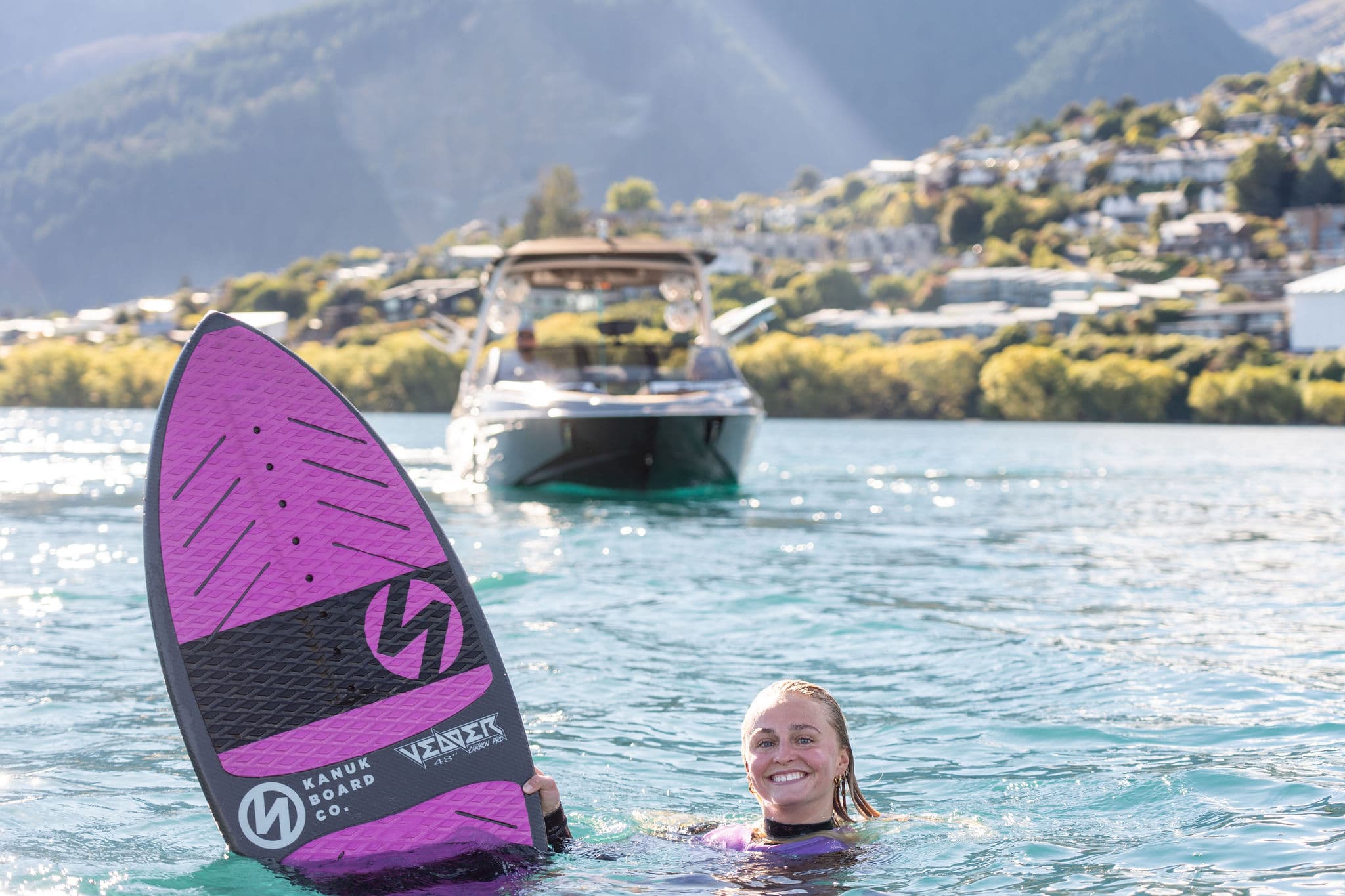Rider in the water beside the board, boat waiting ahead — the getup starting position